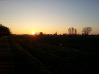 Zicht op Opstal met ondergaande zon bij kerktoren